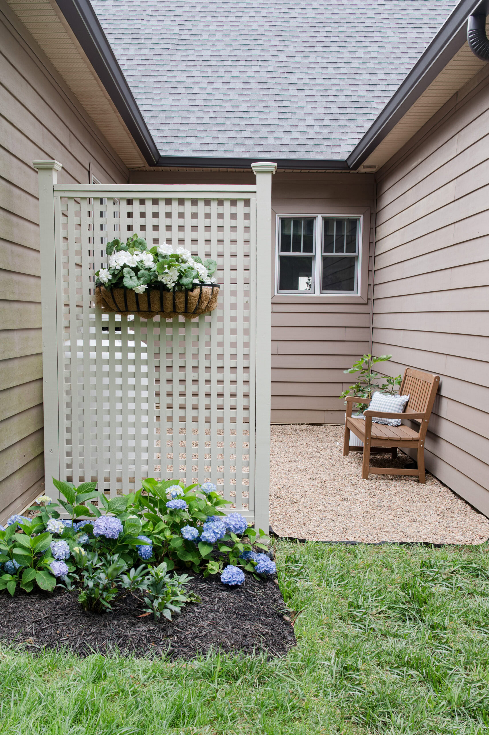 cream lattice fence with bench, hydrangeas and metal window box attached. 