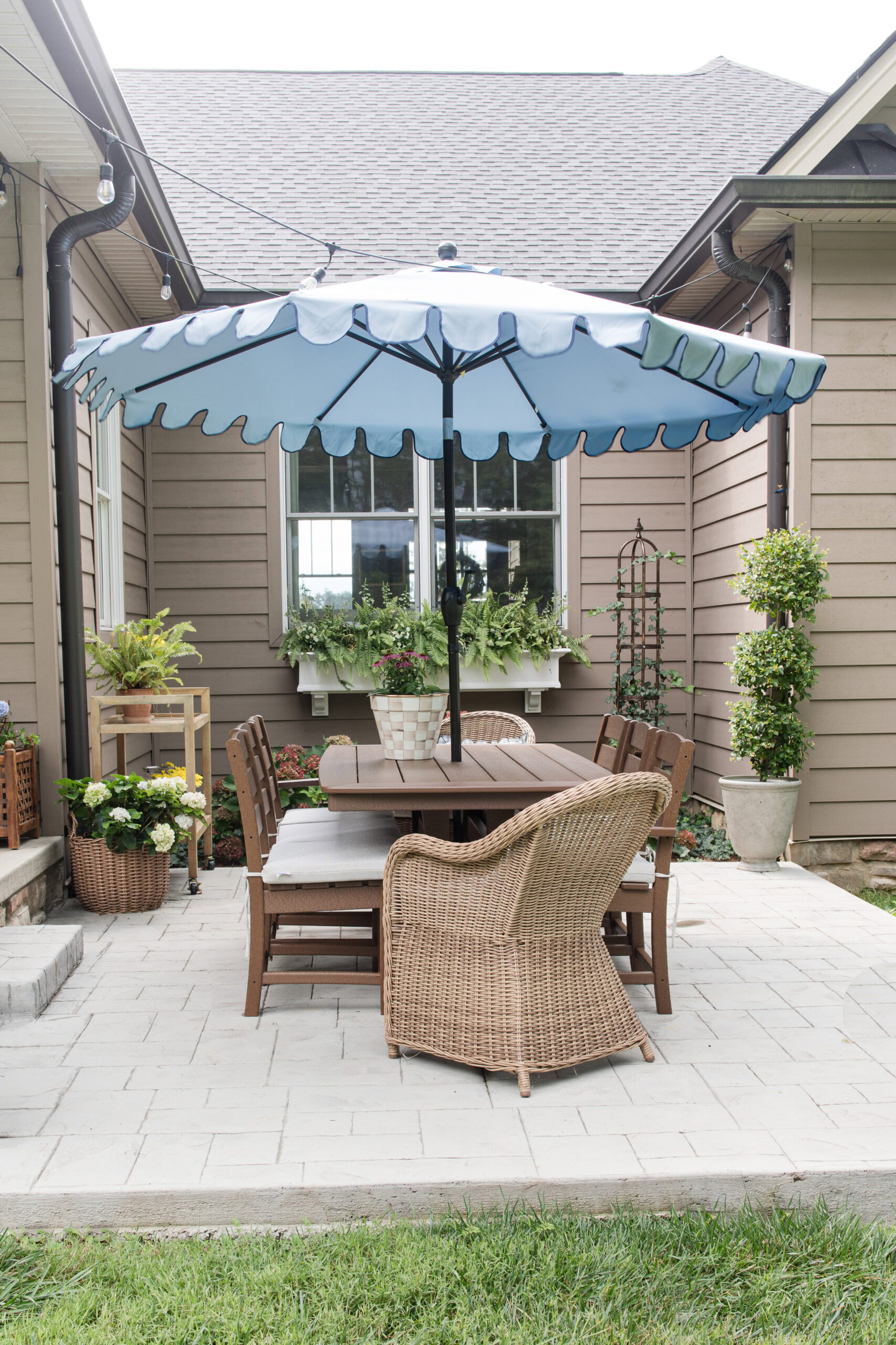 polywood outdoor dining table set on patio with blue umbrella